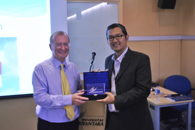 pemberian token of appreciation oleh Dr. Tirta Mursitama kepada Prof. Ron Matthews